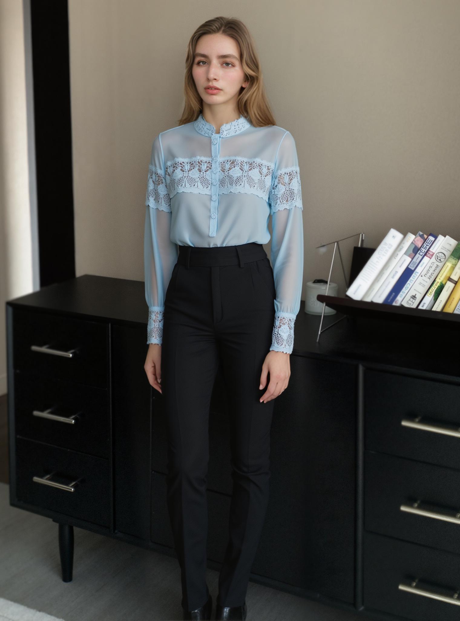 A Woman Stands Elegantly In A Modern Indoor Setting Wearing A Light Blue Lace Blouse And Black Tailored Pants Near A Sleek Black Dresser With Books Displayed