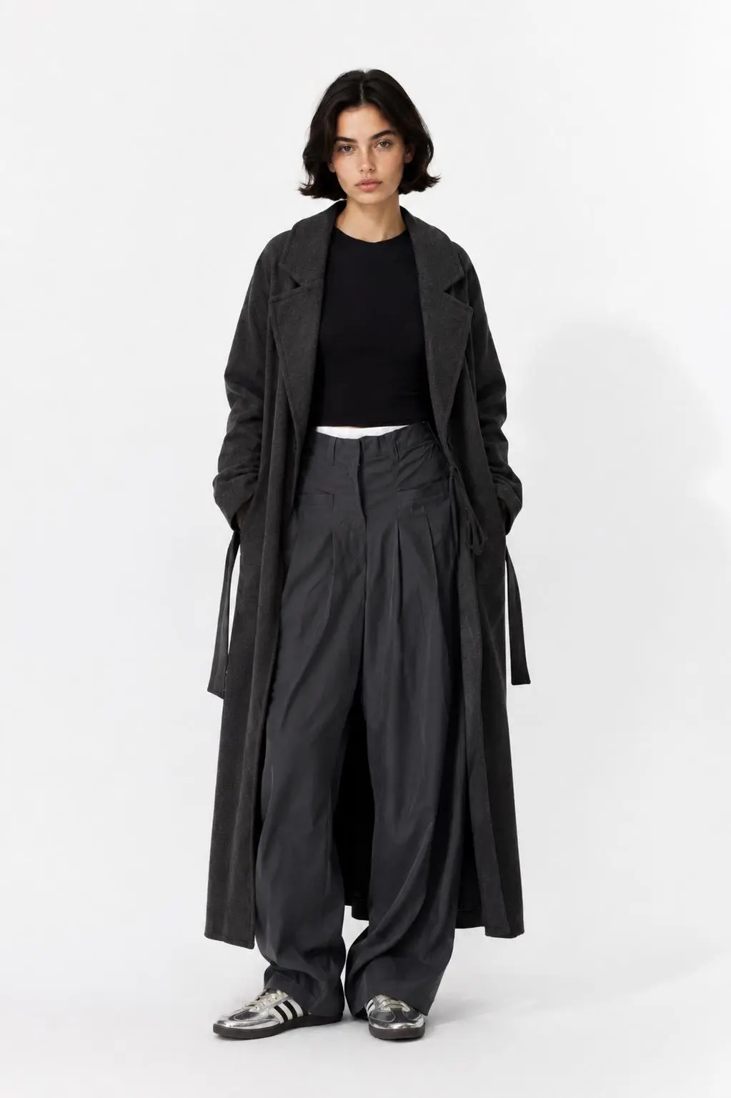 Full-body clothing reference showing a charcoal long coat, black top, oversized dark gray trousers, and silver sneakers