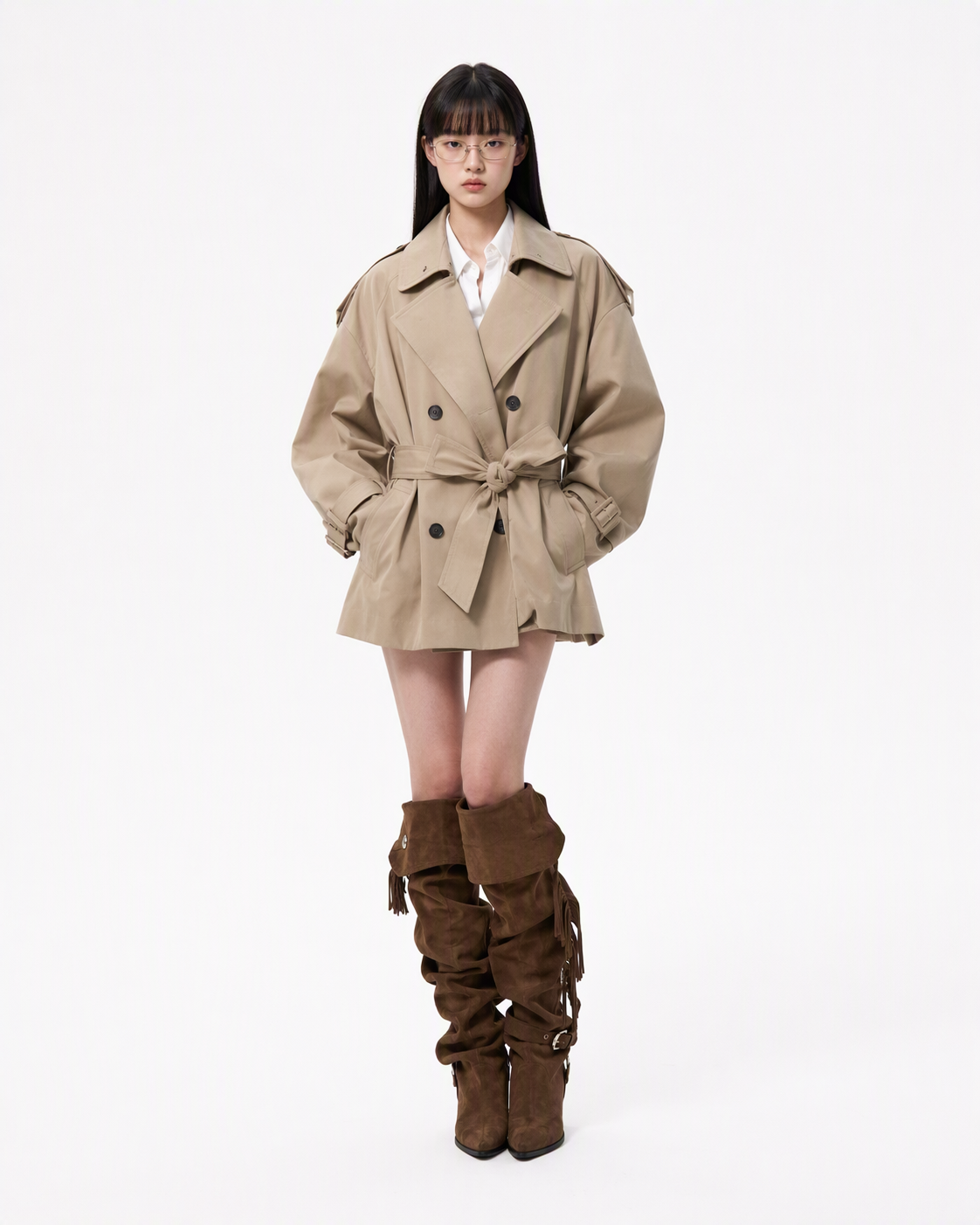 Full-body fashion blogger wearing a beige trench coat, white shirt, glasses, and brown suede boots