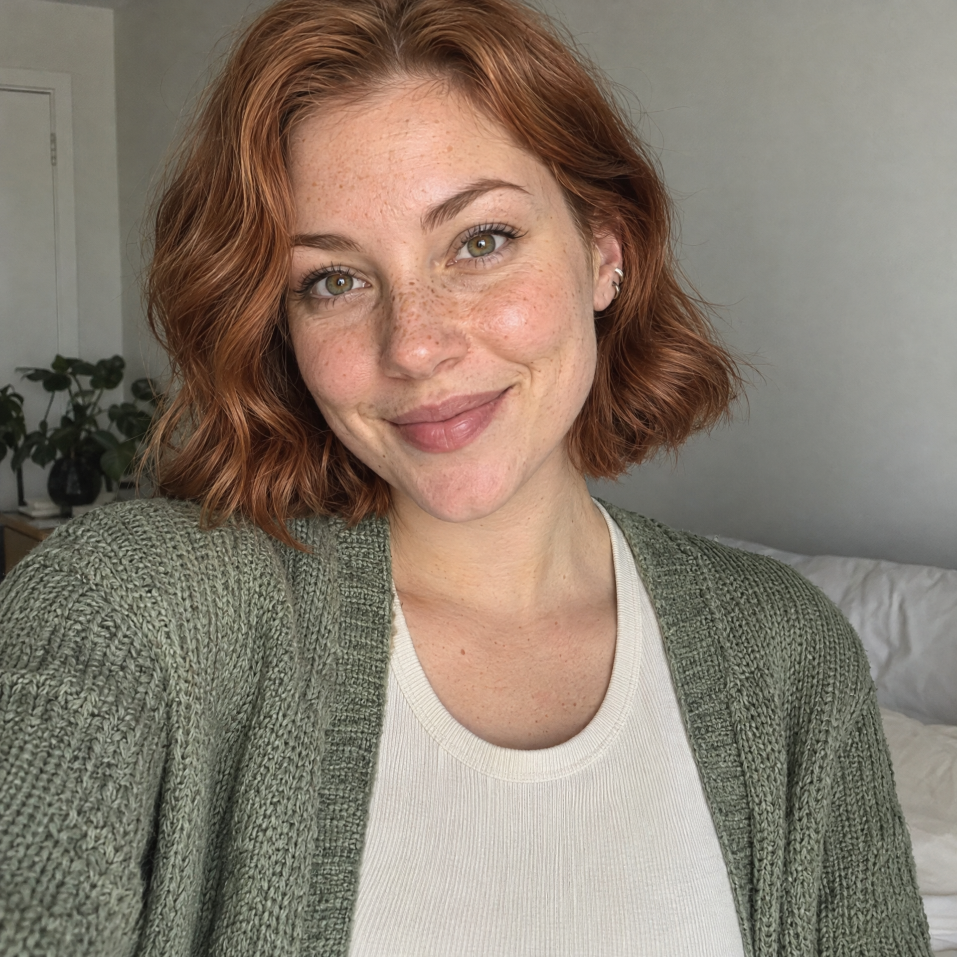 Original selfie of a fictional adult woman with a copper bob and sage cardigan