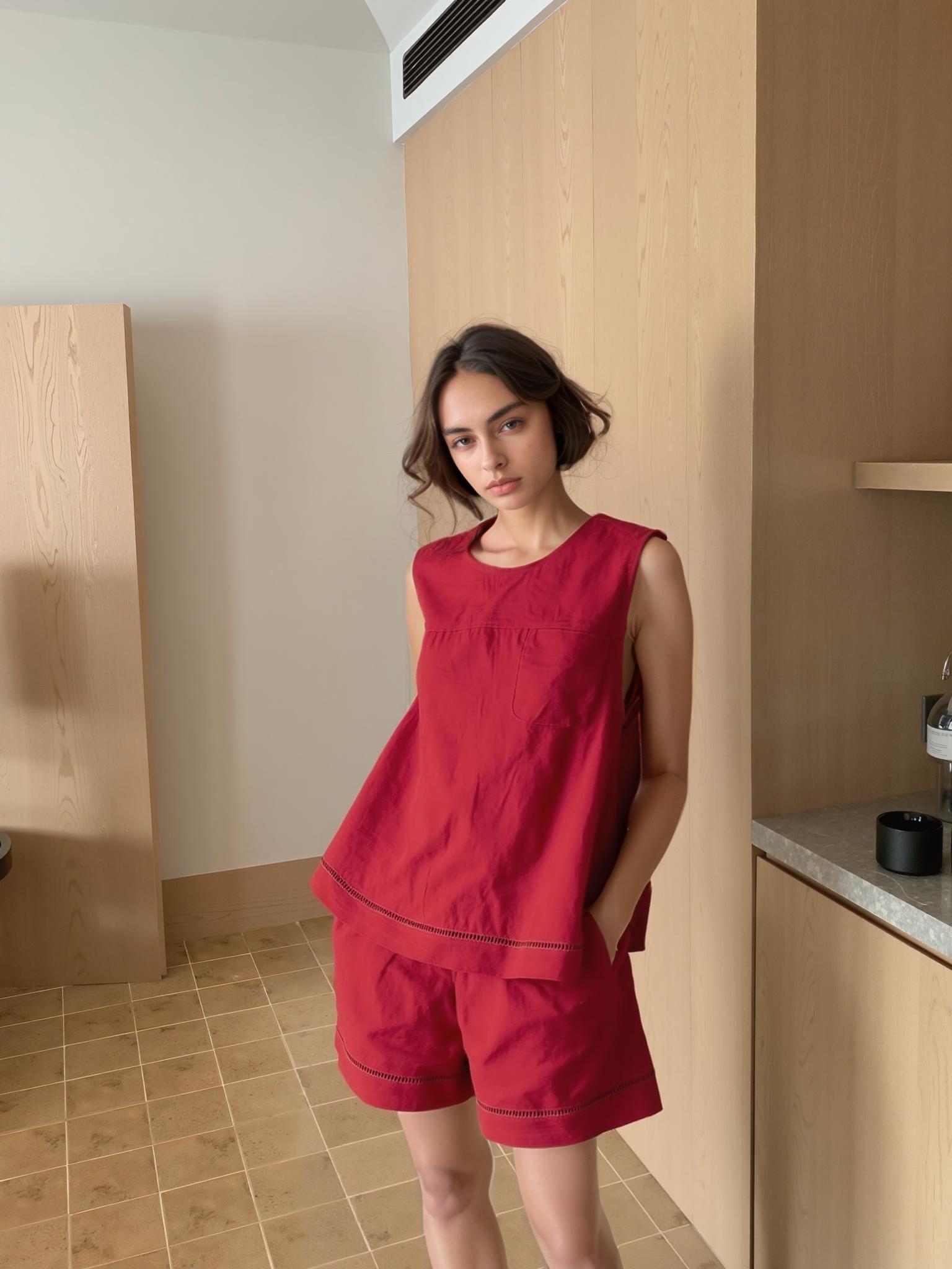 A Woman Stands Indoors Wearing A Red Outfit Set Against A Minimalist Wooden And Tiled Backdrop