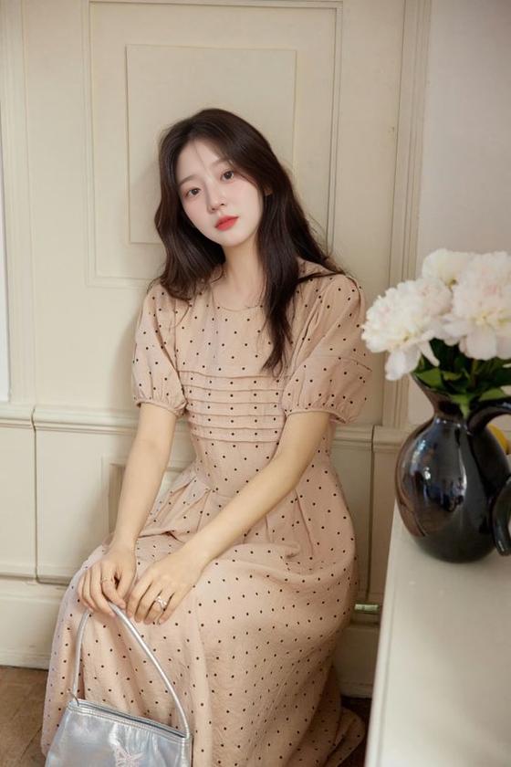 A Woman In A Polka Dot Dress Sits Gracefully By A Table Adorned With White Flowers