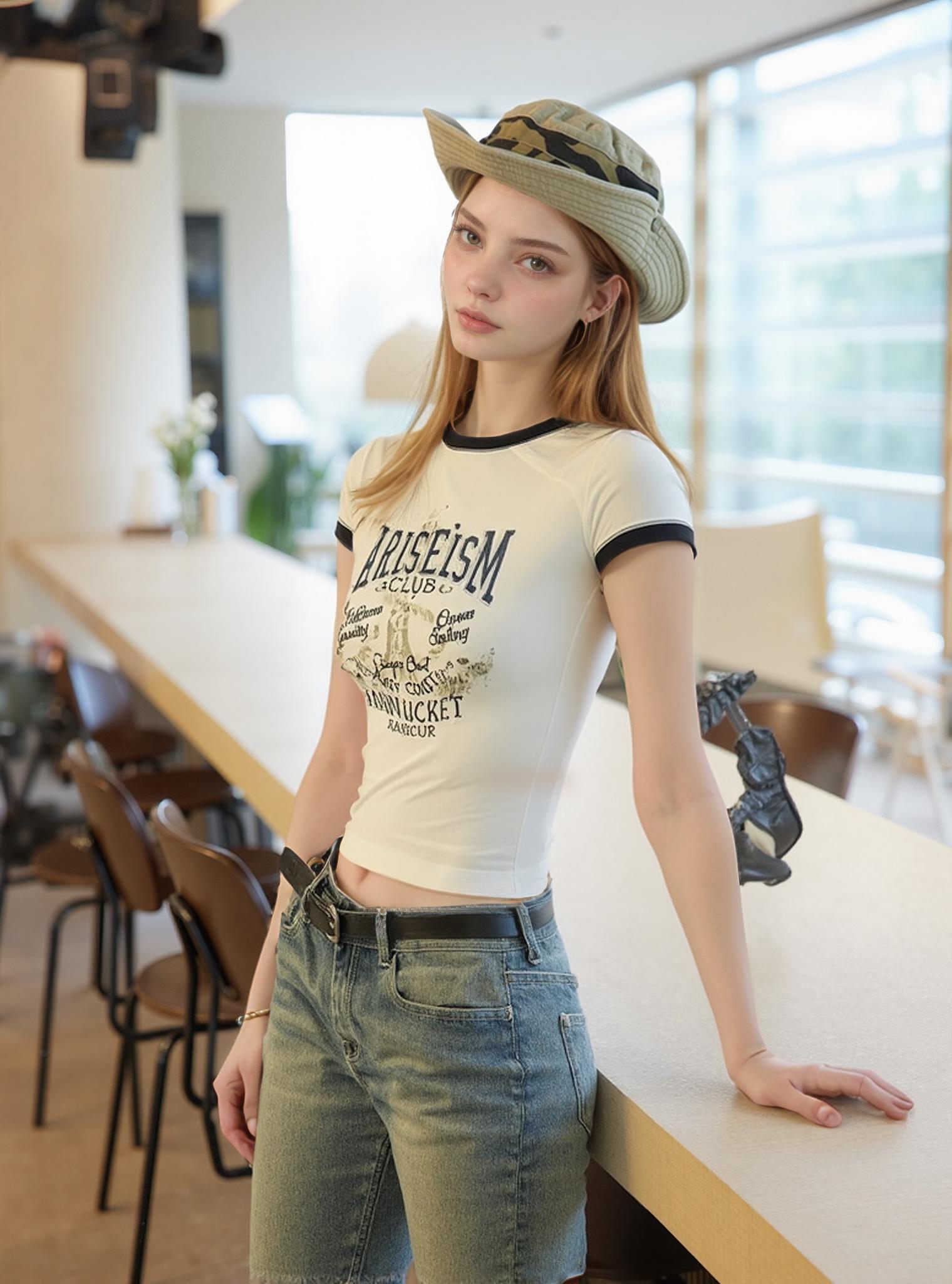 A Woman Wearing Casual Attire And A Camouflage Hat Poses Indoors Near A Modern Wooden Counter In A Bright Open Space